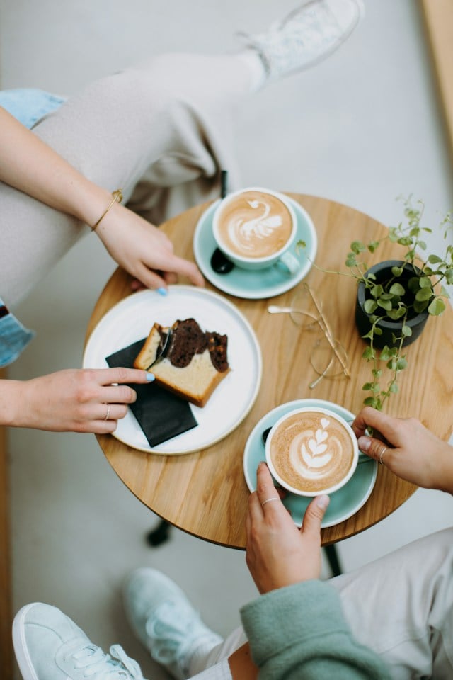 A table with 2 cups of coffee and a slice of cake
