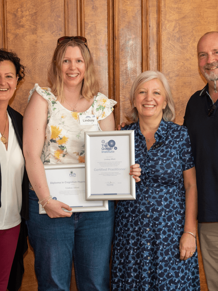 A photo of Lindsay graduating standing next to her tutors holding her qualification certificates