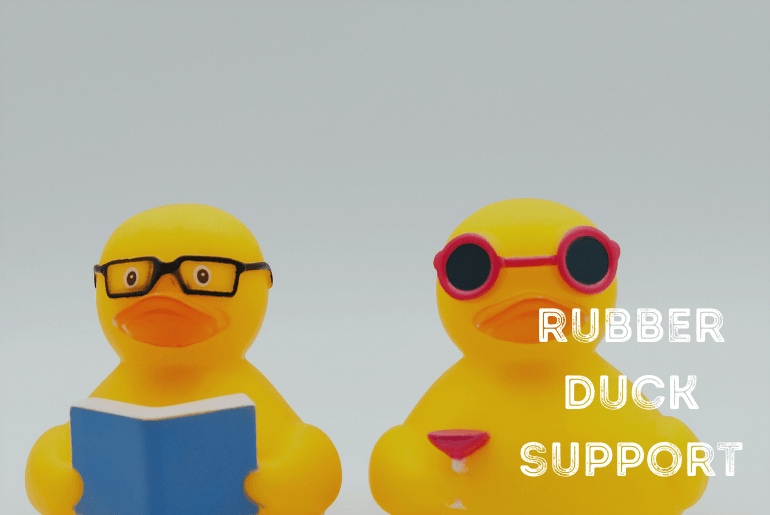 Two yellow rubber ducks sitting next to each other.  One is wearing glasses reading a book and the other is wearing sunglasses holding a martini glass
