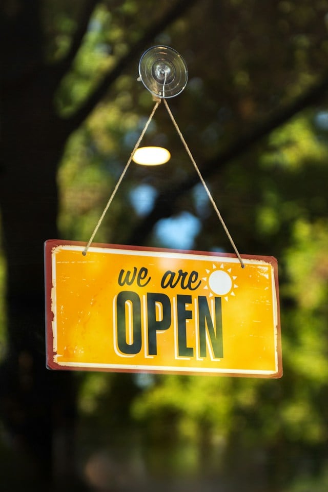 Yellow we are open sign on door window.