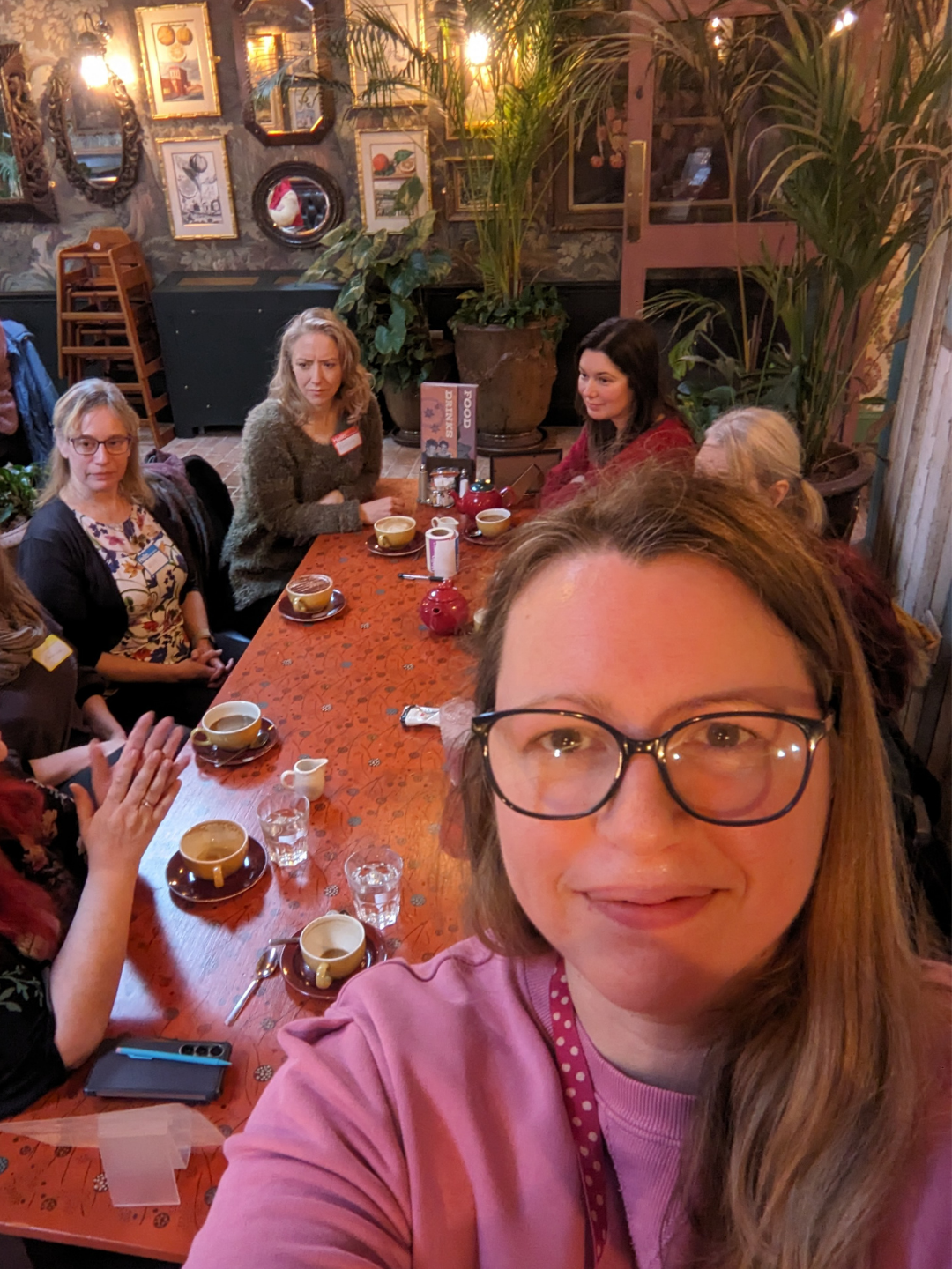 A selfie of Lindsay with attendees of the coffee and chat in the background